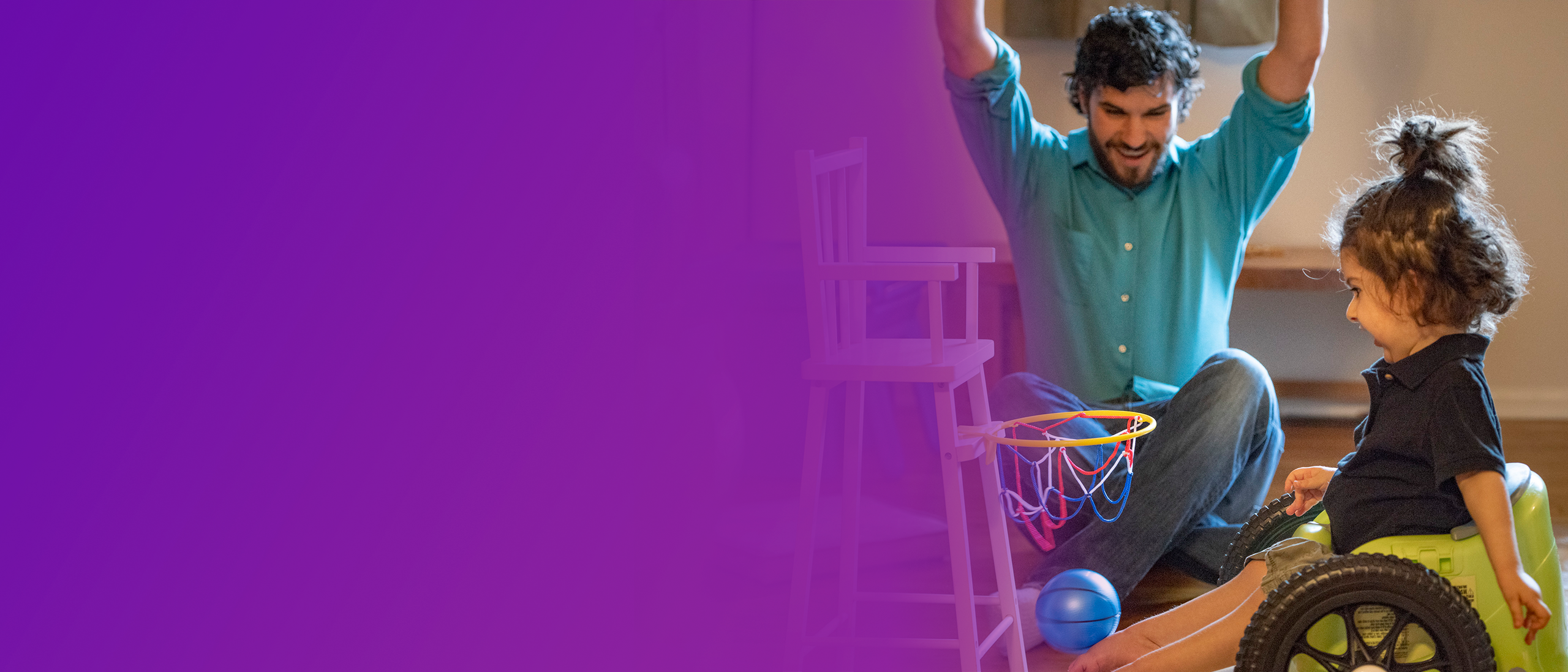 Donovan, a child with SMA, sitting in a wheelchair playing toy basketball with his dad who is sitting on the floor