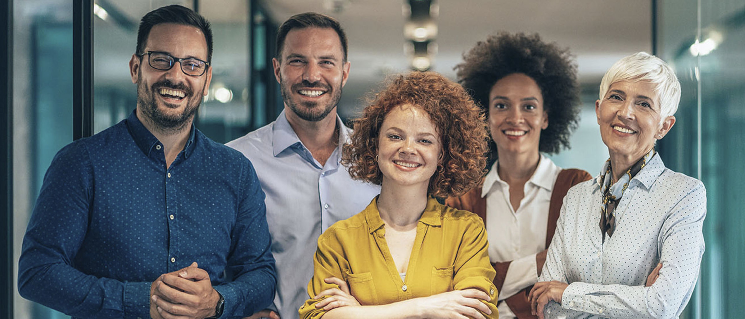 Stock image of 3 women and 2 men looking to the camera and smiling