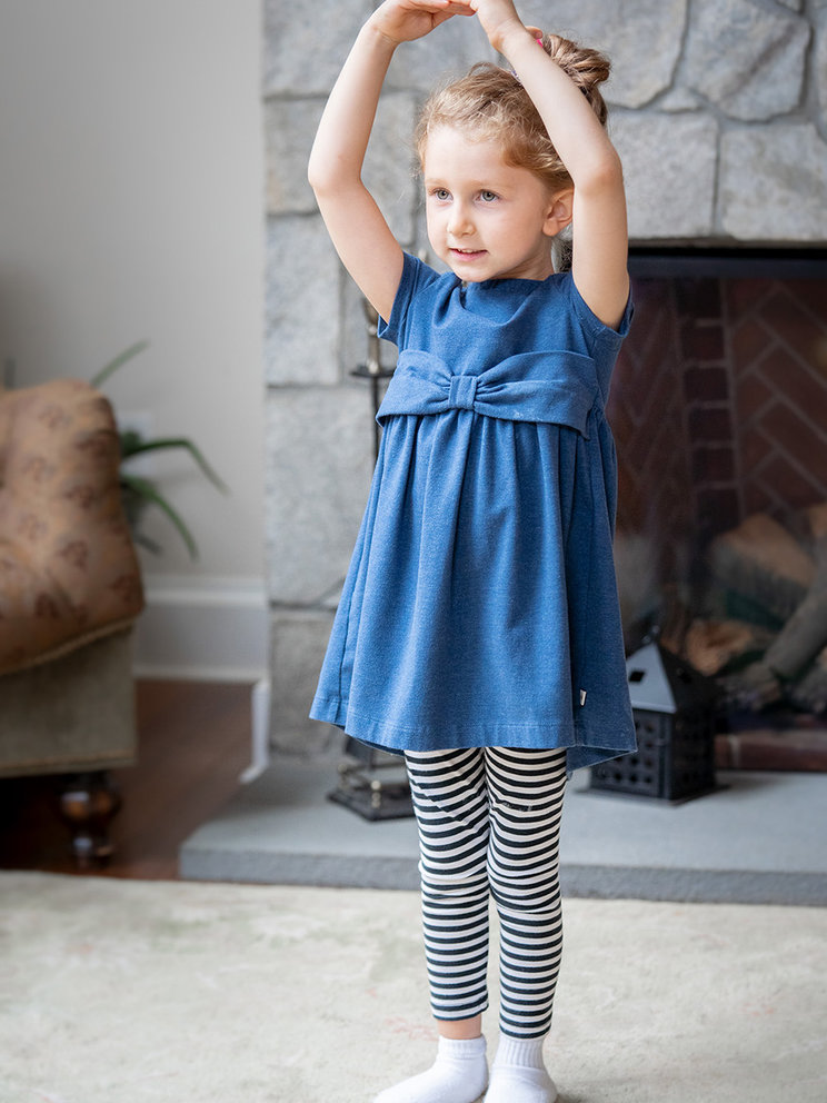 Evelyn at around 5 years old, standing with her arms above her head like a ballerina